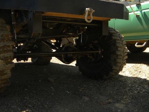 1992 Ford Bronco - The rear suspension and axle of a 1992 Ford Bronco are visible, alongside another green vehicle.