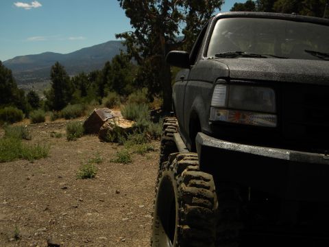 1992 Ford Bronco - A black 1992 Ford Bronco is parked on a dirt road with mountains in the background.