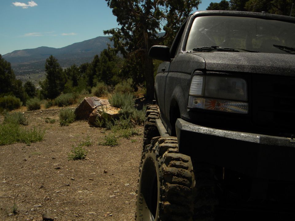 1992 Ford Bronco 3q-front view, black with large tires on a dirt road
