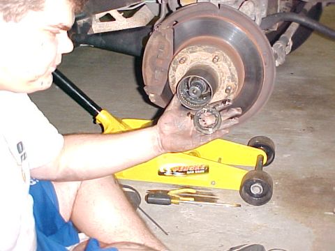 1996 Ford Bronco - Mechanic disassembles a wheel hub, likely for brake service or bearing replacement.
