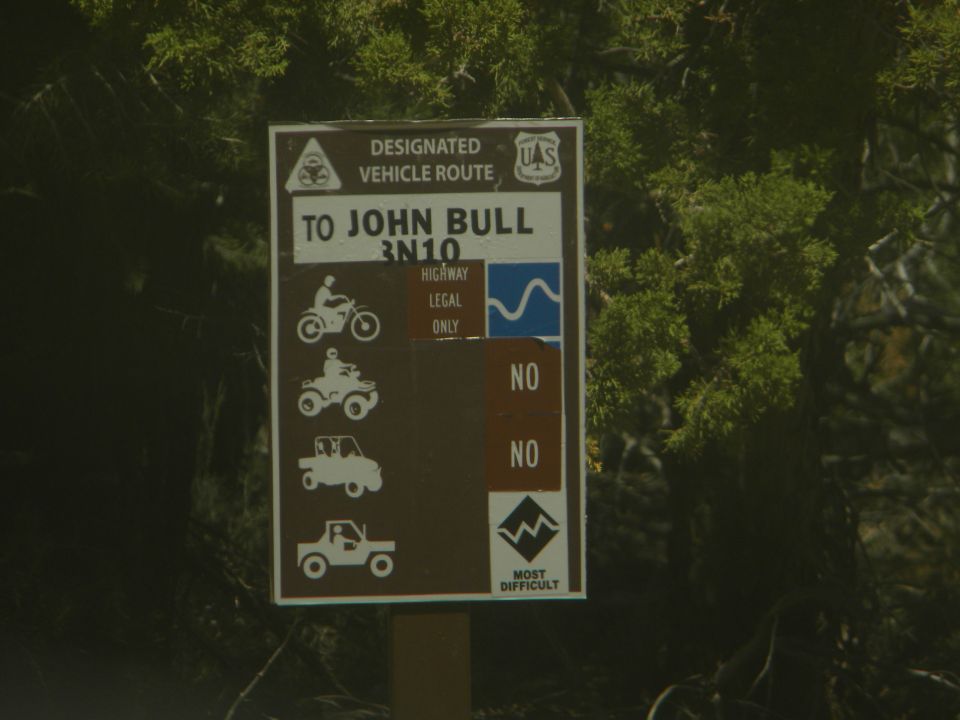 Sign for designated vehicle route to John Bull, showing icons for motorcycle, ATV, and two types of trucks