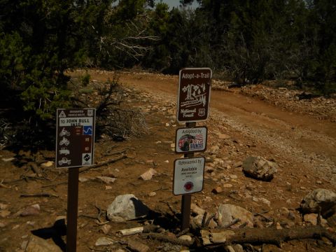 1992 Ford Bronco - Trail signs mark a route in a rocky, wooded area, with one sign indicating adoption by 'So Cal Broncos'.