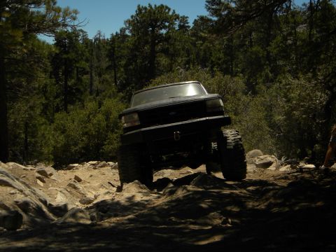 1992 Ford Bronco - A black 1992 Ford Bronco tackles a challenging rocky terrain on an off-road trail.