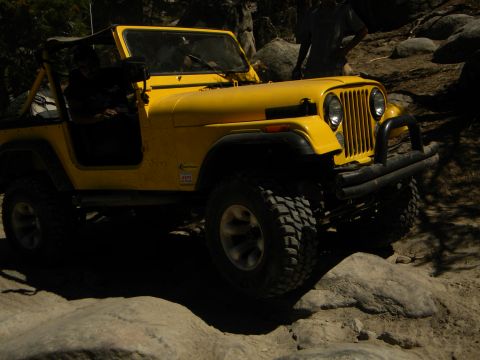 1992 Ford Bronco - A yellow Jeep CJ-7 navigates a rocky trail, displaying the SUPERMOTORS logo.