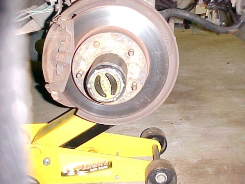 1996 Ford Bronco - Vehicle hub and brake rotor assembly shown on a yellow jack. The hub has a selector with markings.