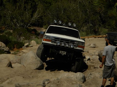 1992 Ford Bronco - A white 1992 Ford Bronco navigates a rocky trail, with another vehicle visible in the background.