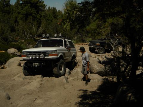 1992 Ford Bronco - A white 1992 Ford Bronco tackles a challenging off-road course, with another Bronco visible in the background.