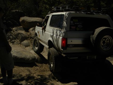 1992 Ford Bronco - White 1992 Ford Bronco navigates a challenging rocky trail with a spare tire on the back.