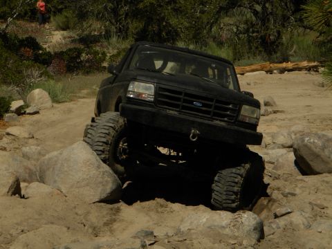 1992 Ford Bronco - An off-road SUV navigates a rocky trail with large tires.