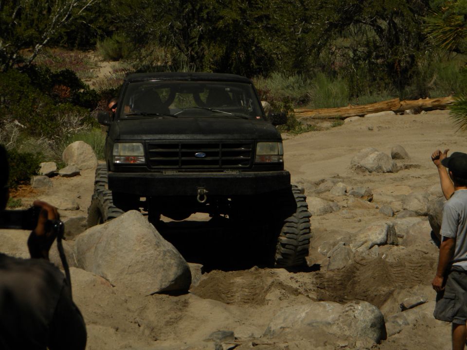 Black 1992 Ford Bronco navigating a rocky trail with people watching