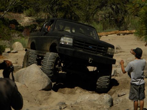 1992 Ford Bronco - A black truck navigates a rocky trail with a spectator observing the action.