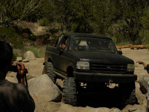 1992 Ford Bronco - A black 1992 Ford Bronco navigates a challenging rocky terrain on an off-road trail.