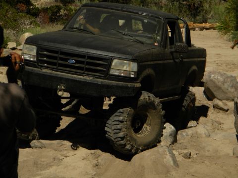1992 Ford Bronco - Black 1992 Ford Bronco tackling a challenging off-road trail with large rocks.