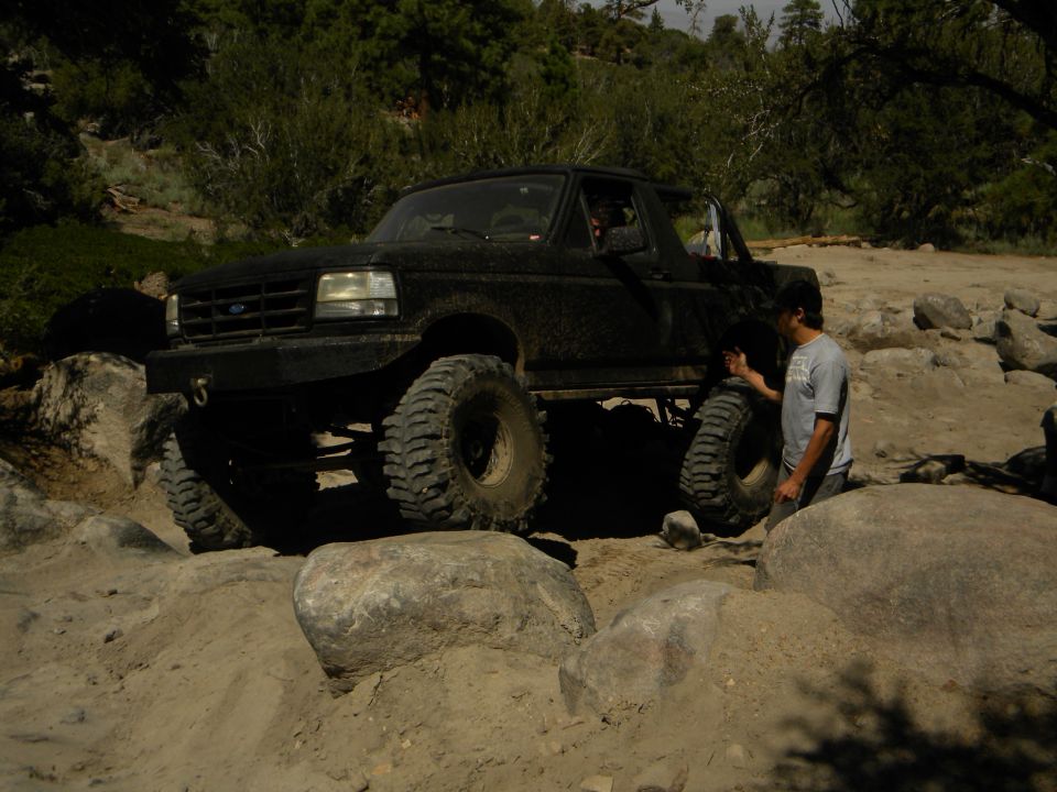 Black 1992 Ford Bronco with large tires navigating rocky terrain