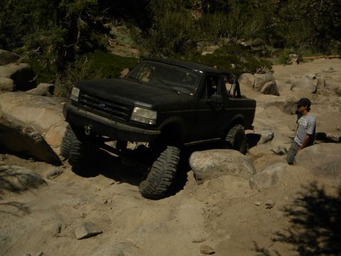 1992 Ford Bronco - 1992 Ford Bronco tackling a challenging off-road course with large boulders.