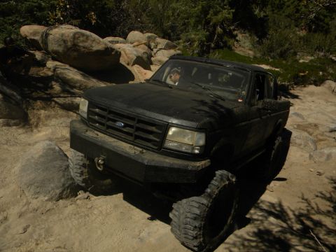 1992 Ford Bronco - This truck is navigating a rocky trail with large tires and a modified bumper.