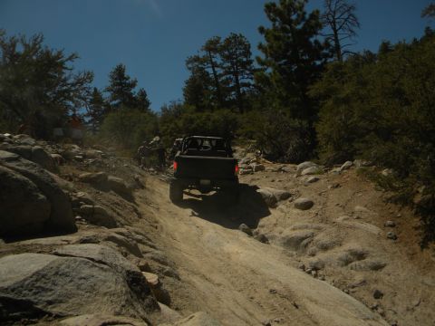 1992 Ford Bronco - Multiple vehicles navigate a challenging rocky trail under a clear blue sky.