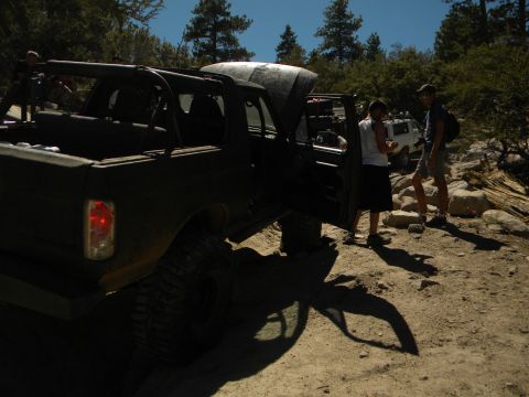 1992 Ford Bronco - A 1992 Ford Bronco is parked on a dirt path with its hood and doors open, while two individuals stand beside it.