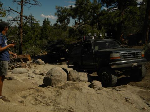 1992 Ford Bronco - A 1992 Ford Bronco navigates a challenging rocky terrain, with a second vehicle following on the trail.