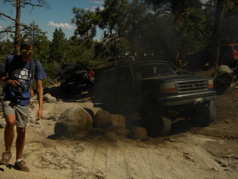 1992 Ford Bronco - A 1992 Ford Bronco navigates a challenging off-road trail with another vehicle visible in the background.