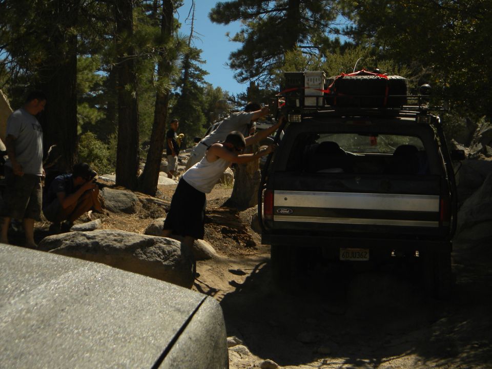 Ford Bronco stuck on rocky trail, people pushing it