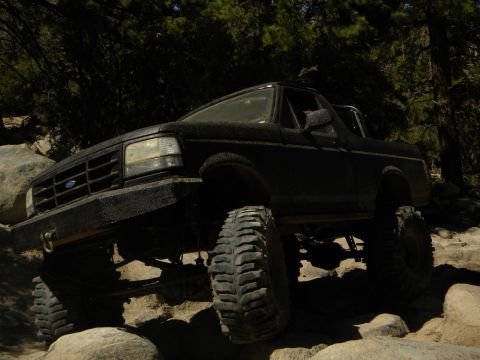 1992 Ford Bronco - A lifted black Ford Bronco navigates a rocky off-road trail.