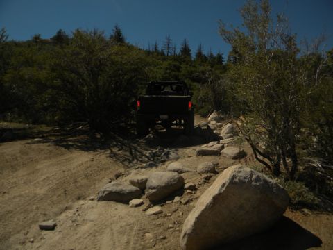 1992 Ford Bronco - Vehicle navigates a challenging rocky path in a wooded, hilly area.