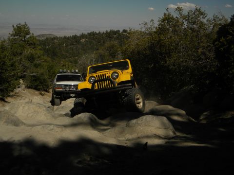 1992 Ford Bronco - Two off-road vehicles tackle a challenging rocky path under a clear sky.