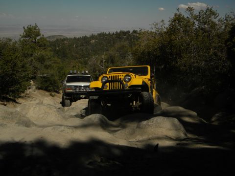 1992 Ford Bronco - Two off-road vehicles navigate a challenging rocky terrain under a clear sky.