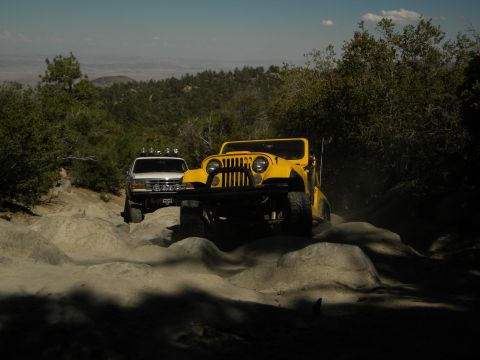 1992 Ford Bronco - Two off-road vehicles navigate a challenging rocky path under a clear sky.