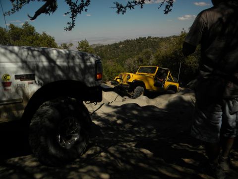 1992 Ford Bronco - Two off-road vehicles navigate a challenging rocky trail under a clear blue sky.