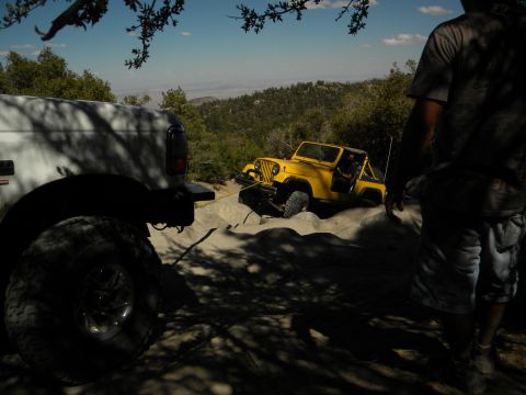 1992 Ford Bronco - Two Jeeps navigating a challenging off-road trail with a scenic mountain vista in the background.