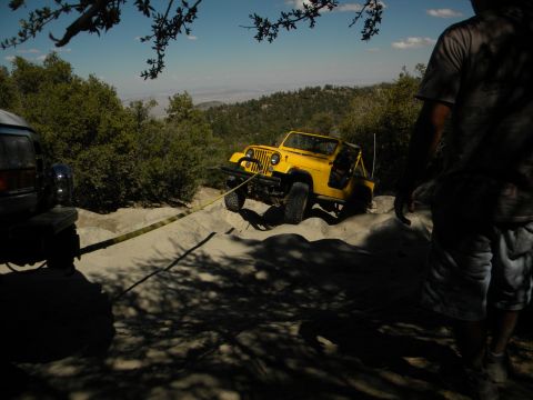 1992 Ford Bronco - A yellow Jeep is being winched up a sandy incline by a dark SUV on an off-road trail.