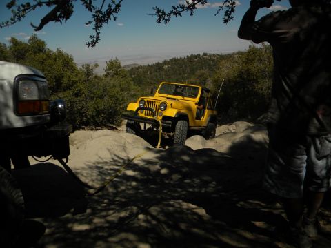 1992 Ford Bronco - Two off-road vehicles navigate a rocky trail under a clear blue sky.