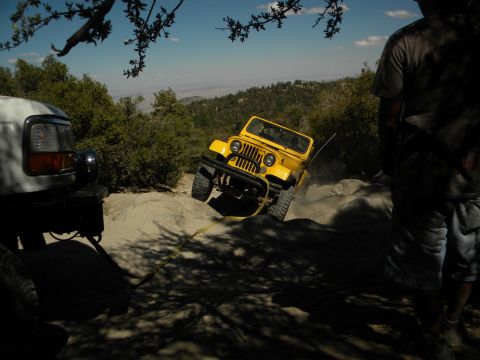 1992 Ford Bronco - A yellow Jeep CJ-5 navigates a steep, rocky trail with assistance from a white SUV.