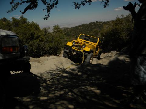 1992 Ford Bronco - Two off-road vehicles navigate a challenging rocky trail under a clear blue sky.