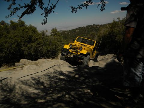 1992 Ford Bronco - A yellow Jeep Wrangler navigates a rocky trail with a tow strap attached.