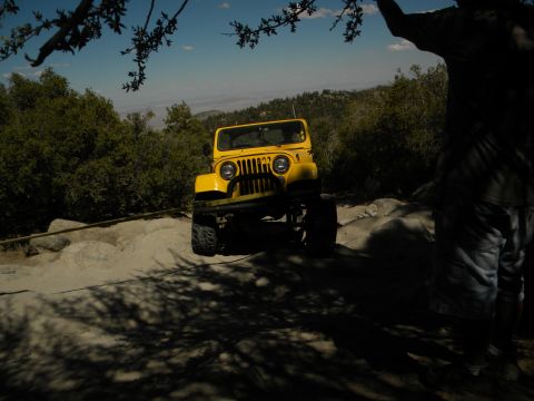 1992 Ford Bronco - A yellow Jeep CJ navigates a , off-road path under a clear blue sky.