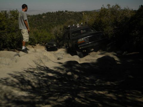 1992 Ford Bronco - A 1992 Ford Bronco navigates a challenging rocky terrain, with another vehicle visible in the background.