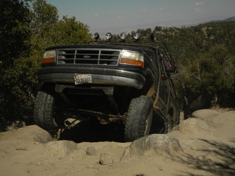 1992 Ford Bronco - A black 1992 Ford Bronco navigates a challenging rocky path off-road.