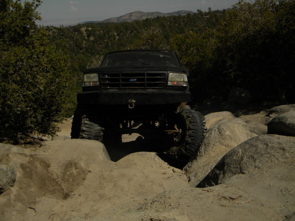 Black SUV with large tires navigating rocky terrain
