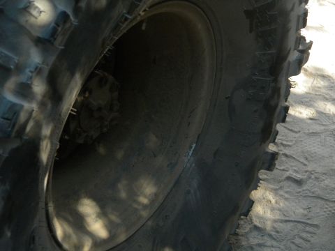 Close-up of a large off-road tire and wheel, showing tread detail and part of the hub