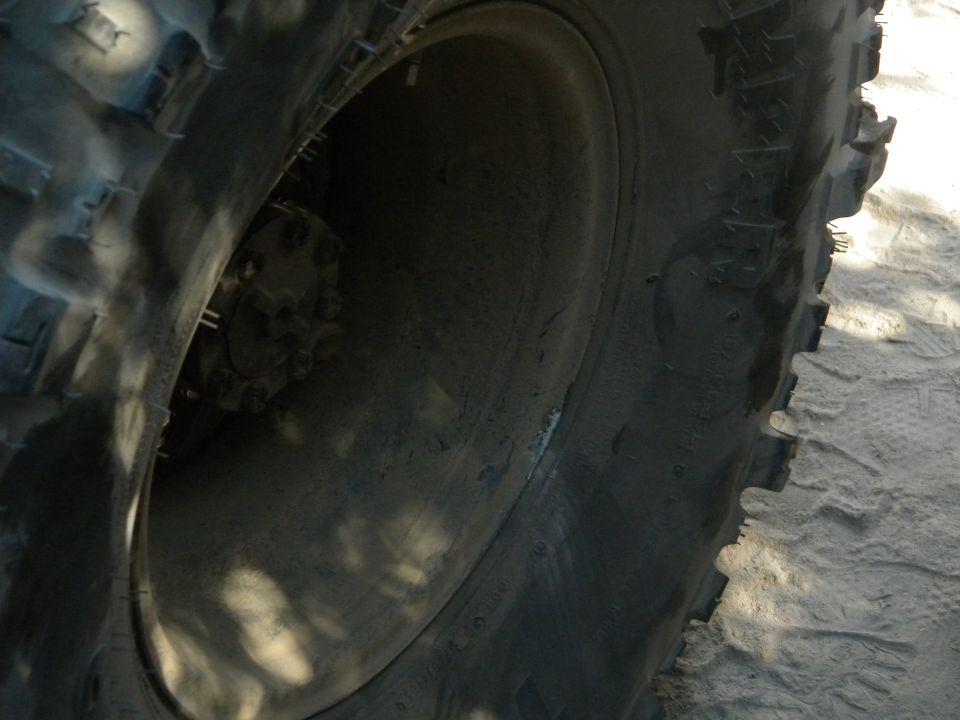 Close-up of a large off-road tire and wheel, showing tread detail and part of the hub