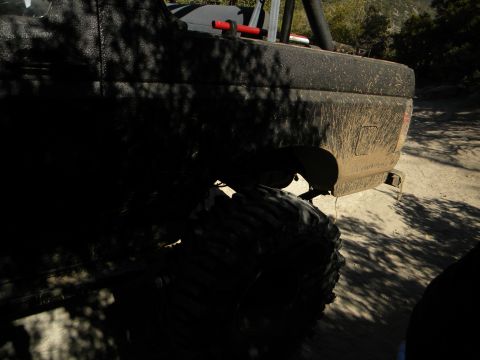 Muddy off-road truck with large tires, seen from the rear quarter