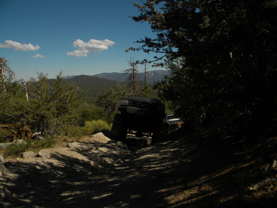 Black off-road vehicle driving on a rocky trail with another vehicle behind it