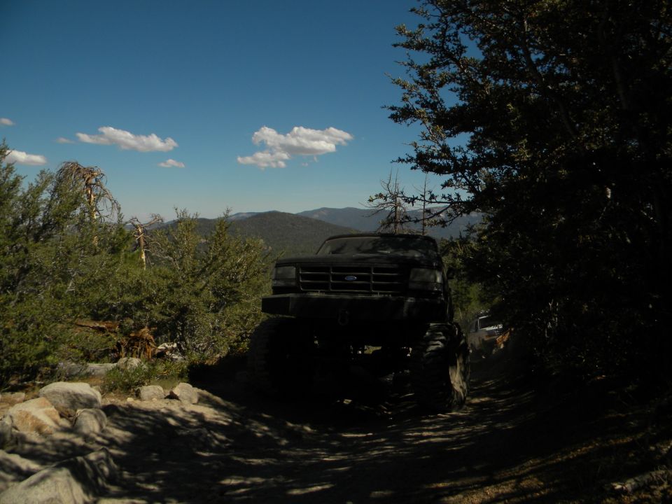 Black 1992 Ford Bronco on a dirt road, front 3/4 view, lifted suspension, off-road tires