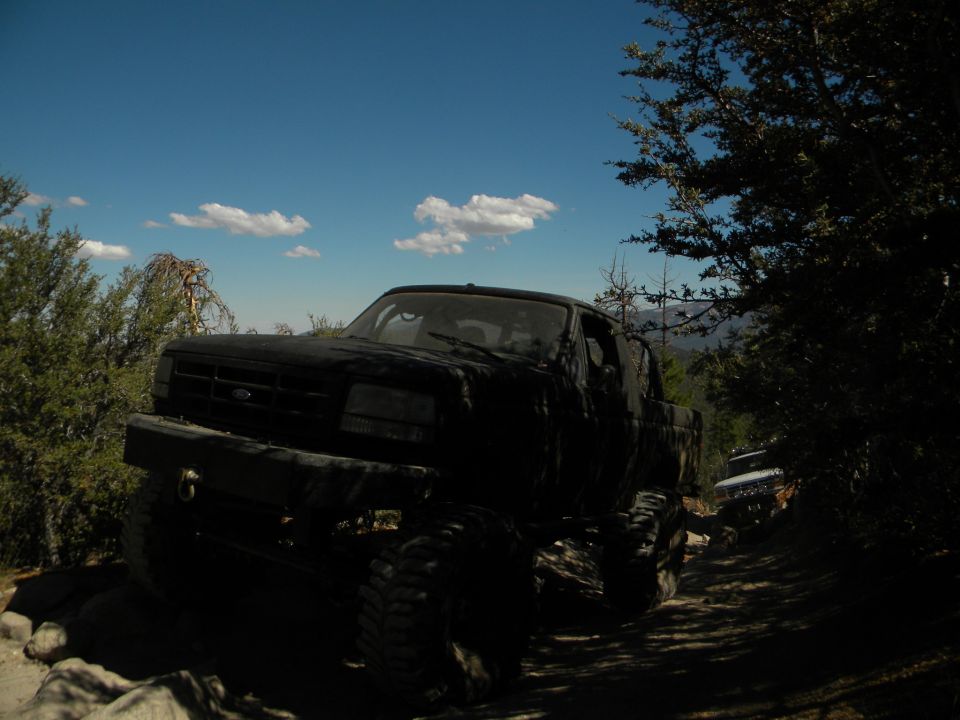 Black 1992 Ford Bronco on a rocky, wooded trail, front-left view