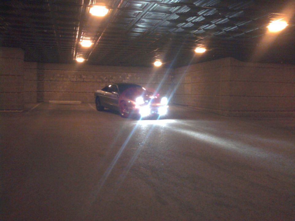 car with headlights on in a parking garage