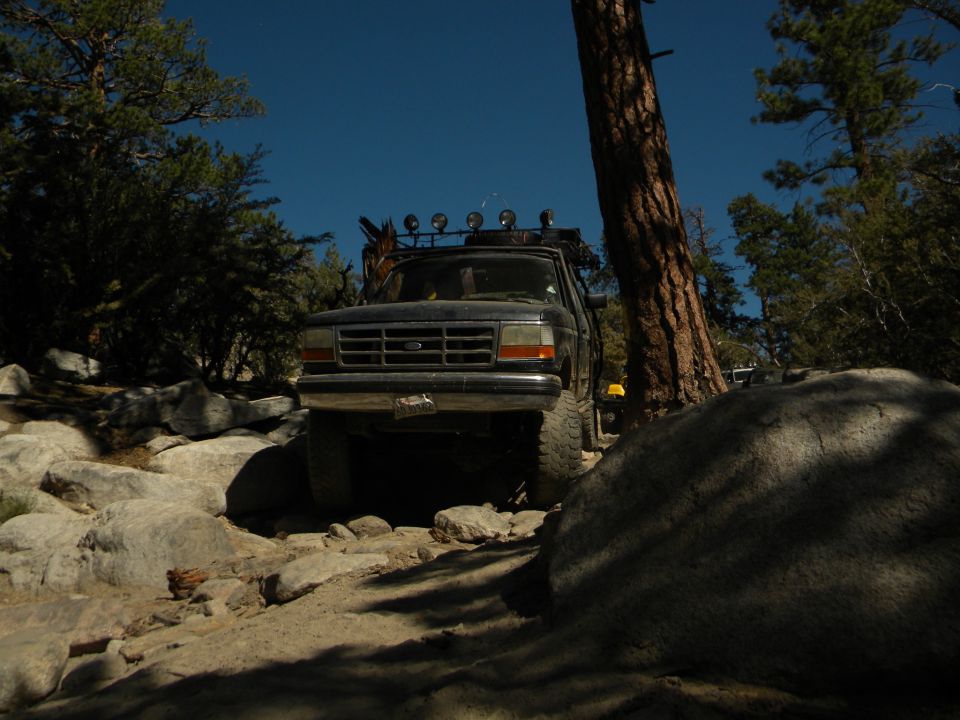Ford F-Series truck on a rocky trail, front view. It has a roof rack with lights