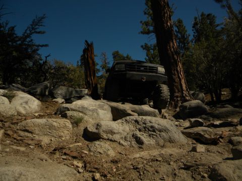 Black 1992 Ford Bronco driving over rocks on a trail